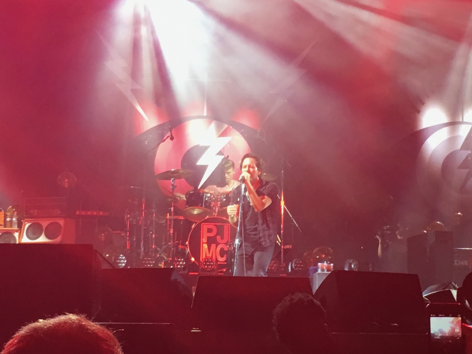 Eddie Vedder singing into a microphone on a red-lit stage