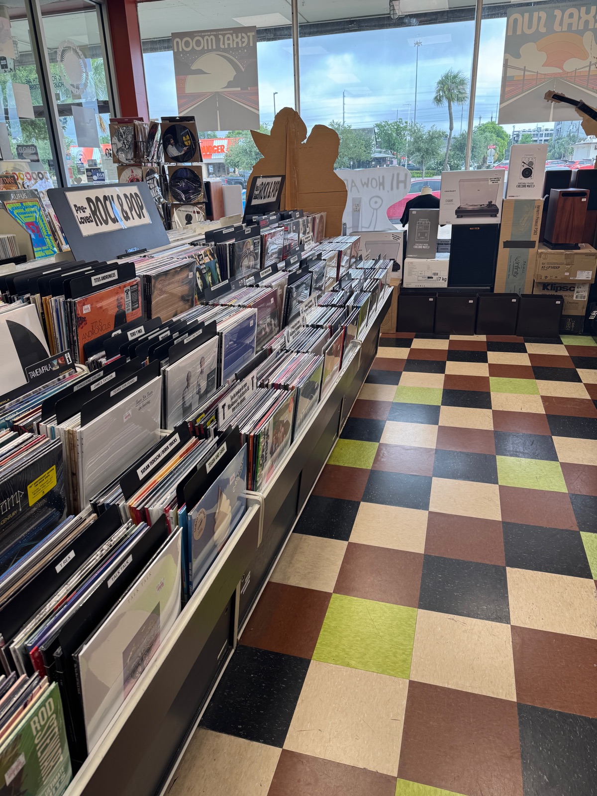 Aisle of record bins at a record store with a checkered floor