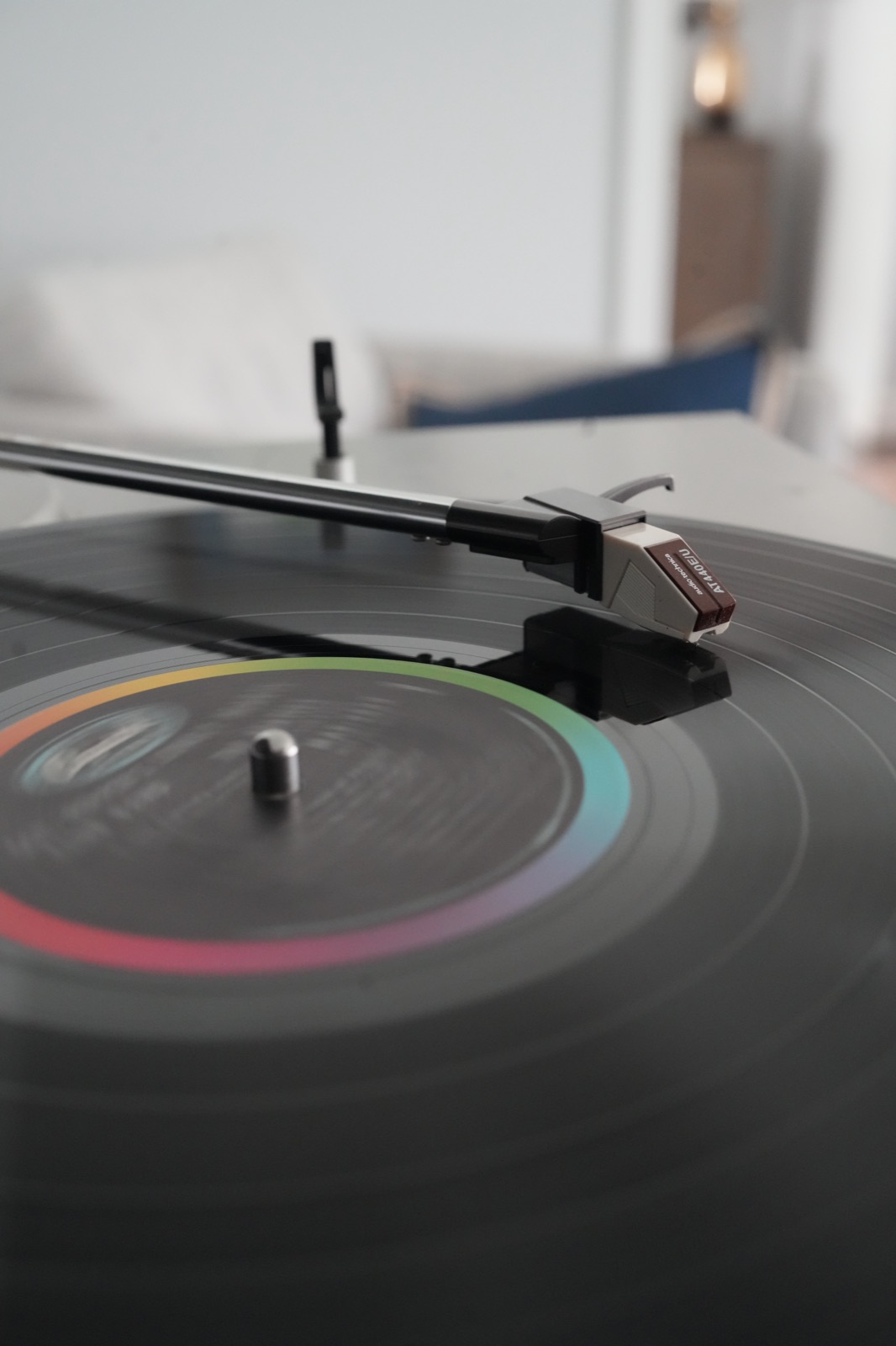 Close-up of a turntable tonearm and cartridge resting on a spinning record